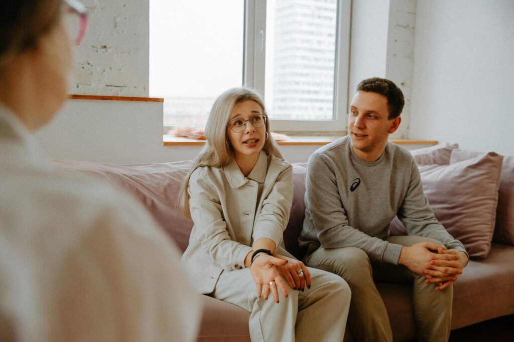 A couple and therapist engaged in a discussion during a therapy session indoors.